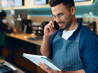 restaurant manager taking a call behind bar while holding notebook